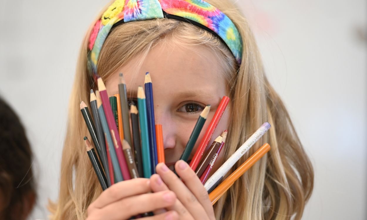 young student with colored pencils